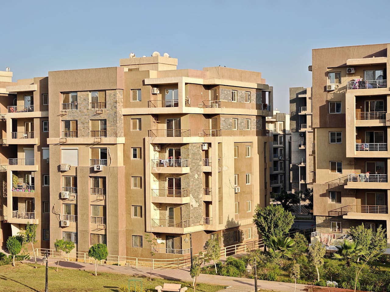 A modern apartment complex with multiple buildings in a sunny urban environment, showcasing contemporary architecture.