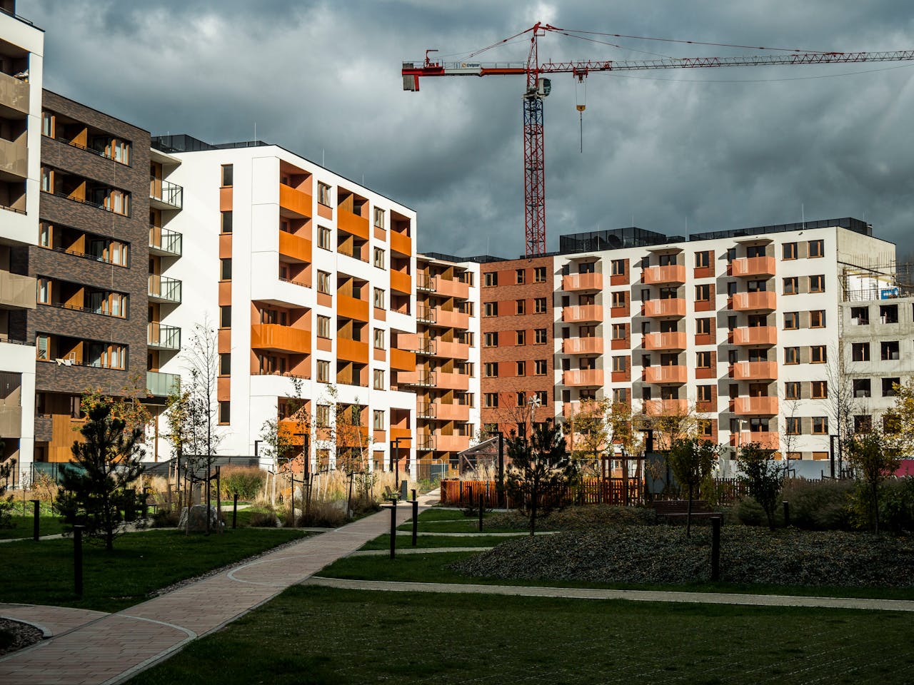 Newly built residential buildings under cloudy skies with a construction crane.