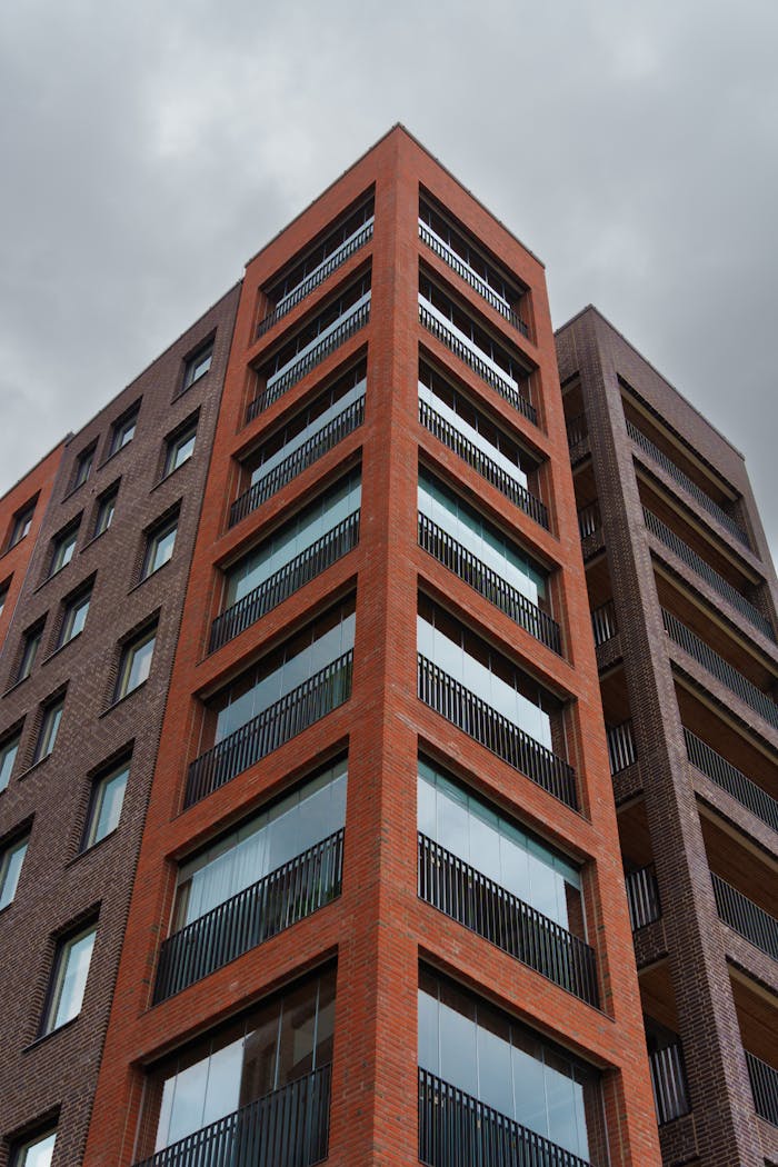 Low angle view of a modern apartment building against a grey sky.